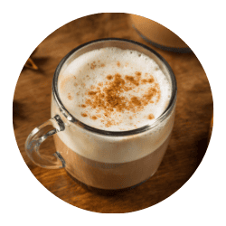 Delicious Indian chai tea with frothy milk and spices, served in a clear glass mug. Perfect for authentic Indian beverage lovers seeking rich, flavorful drinks.