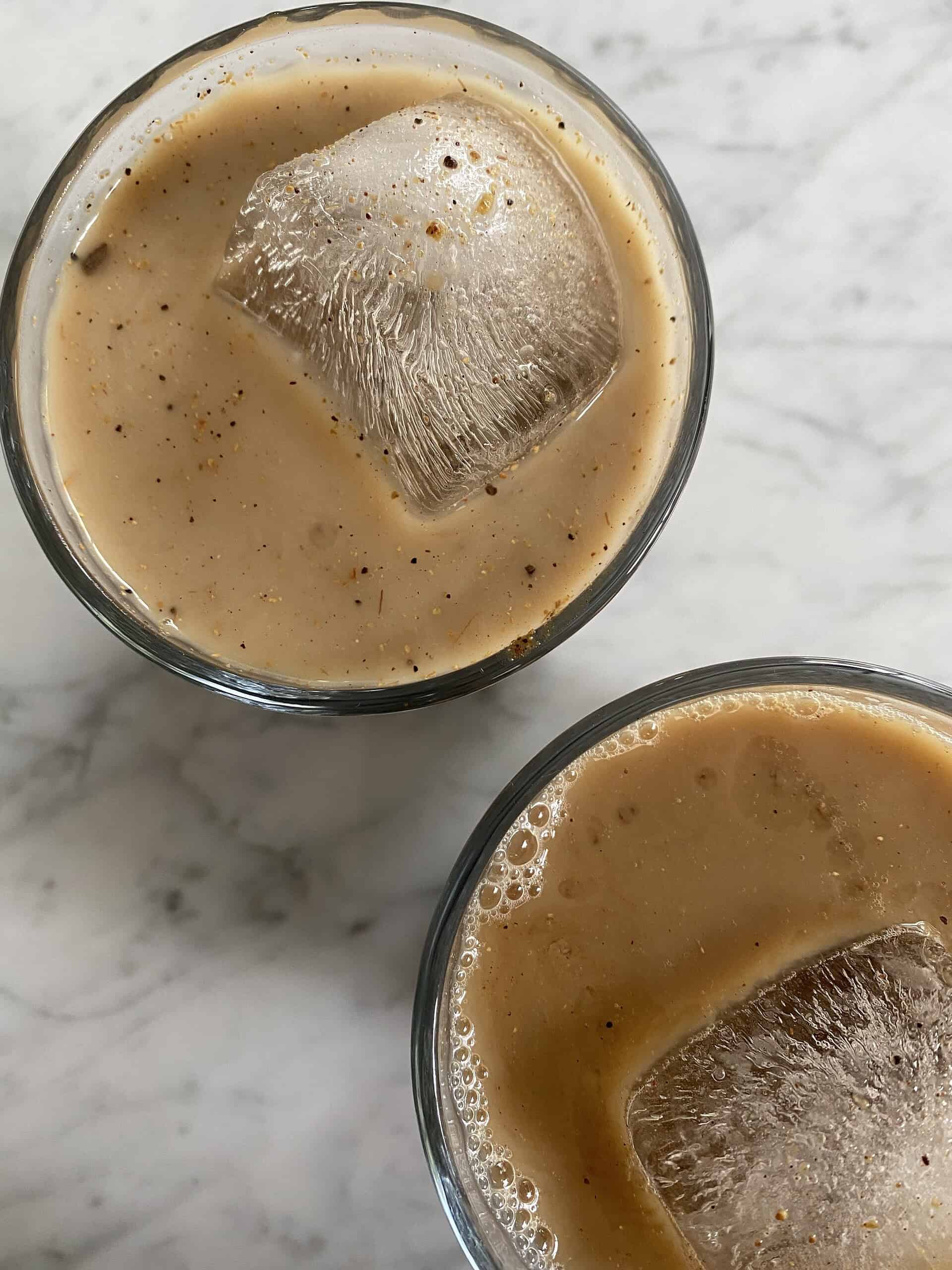 A vibrant image of chilled Indian iced tea with ice cubes, featuring traditional spices like cinnamon and cardamom, served in clear glasses.